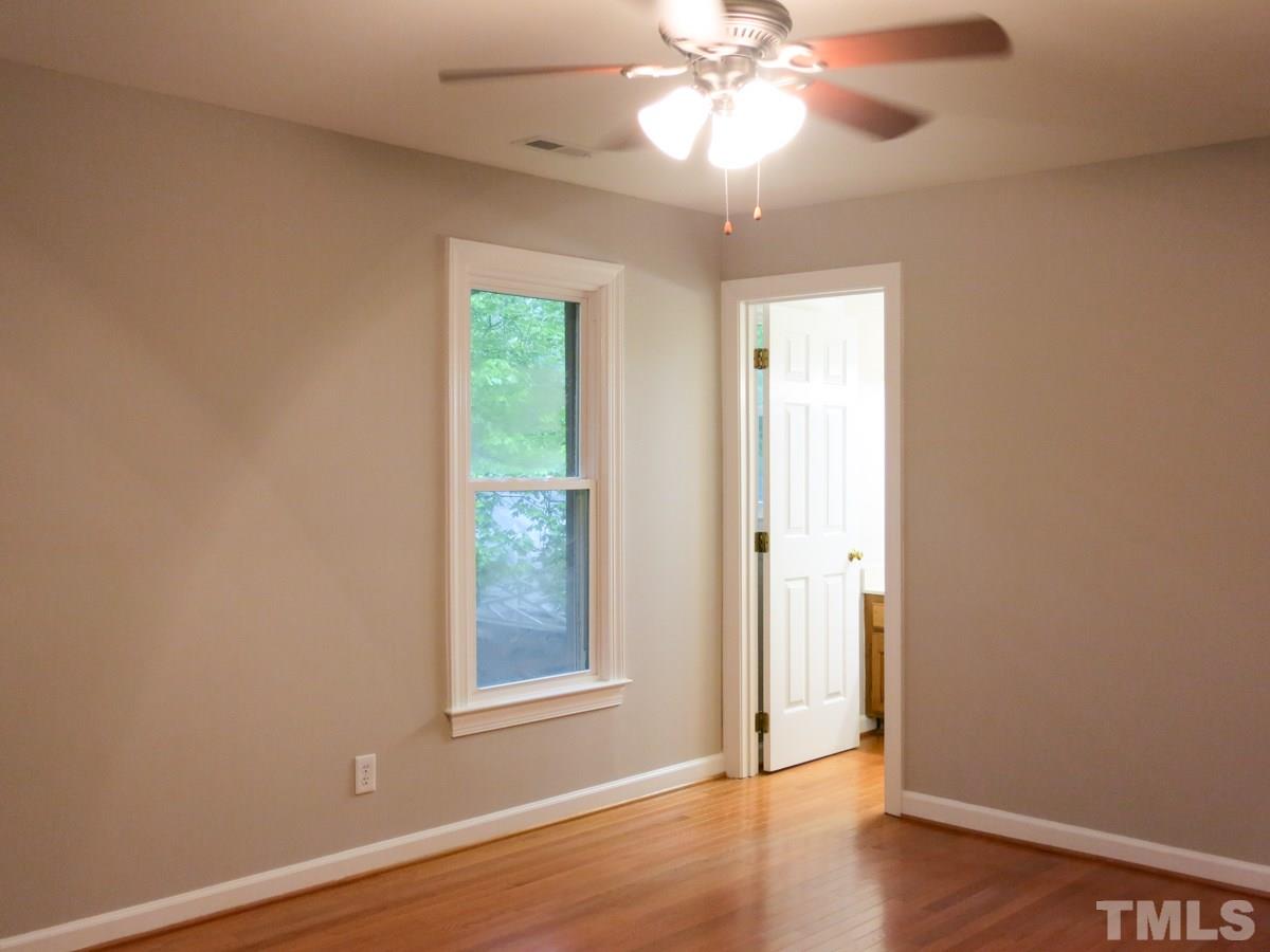 6820 Gloucester Road Raleigh, NC 27612 - Photo 15 of 25 an empty room with wooden floor chandelier fan and windows