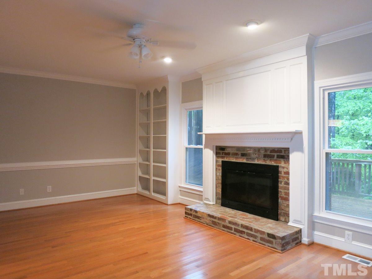 6820 Gloucester Road Raleigh, NC 27612 - Photo 3 of 25 an empty room with wooden floor fireplace and windows
