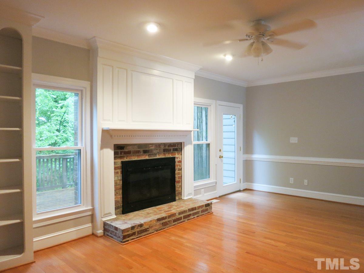 6820 Gloucester Road Raleigh, NC 27612 - Photo 4 of 25 a view of an empty room with wooden floor fireplace and a window