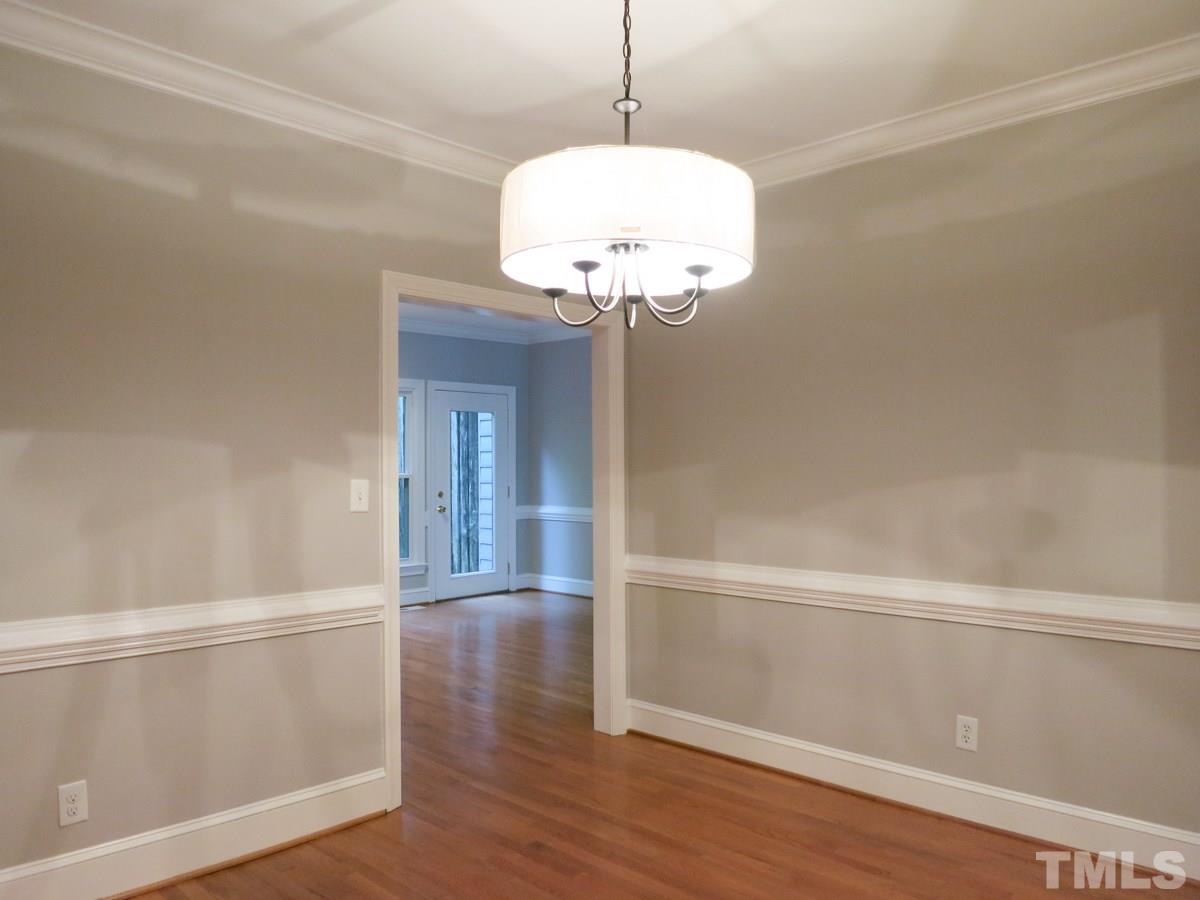 6820 Gloucester Road Raleigh, NC 27612 - Photo 6 of 25 a view of a hallway with wooden floor and chandelier