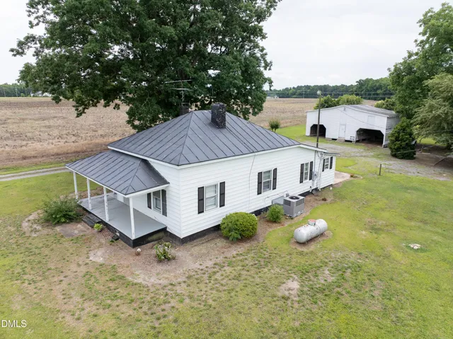 a view of a white house with a big yard and large trees
