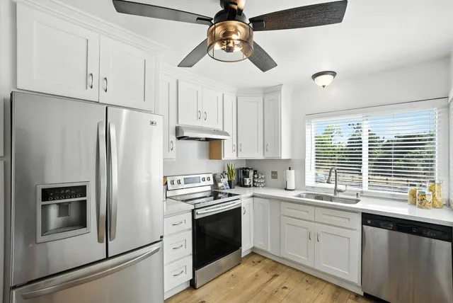 a kitchen with stainless steel appliances white cabinets and a refrigerator