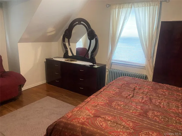 a bedroom with a bed and a dresser next to a window