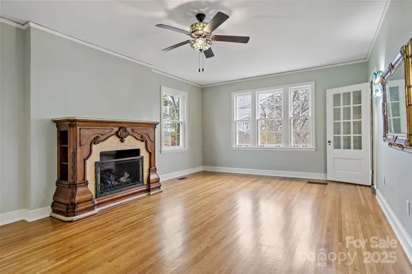 a view of an empty room with wooden floor fireplace and a window