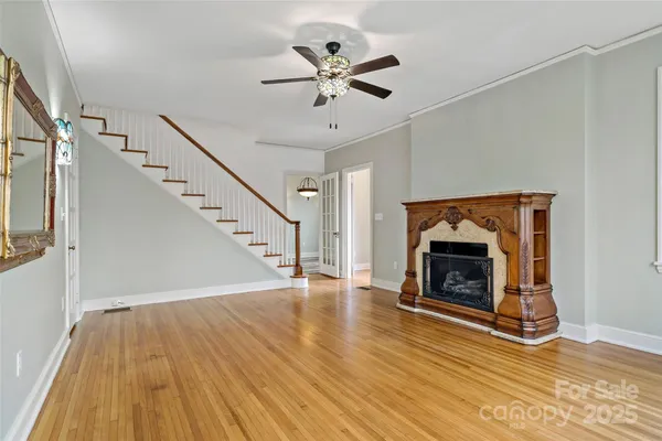 a view of an empty room with wooden floor and a ceiling fan