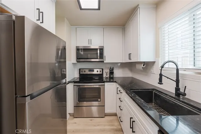 a kitchen with stainless steel appliances granite countertop a refrigerator sink and stove