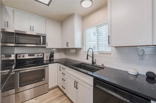 a kitchen with granite countertop a sink stainless steel appliances and cabinets
