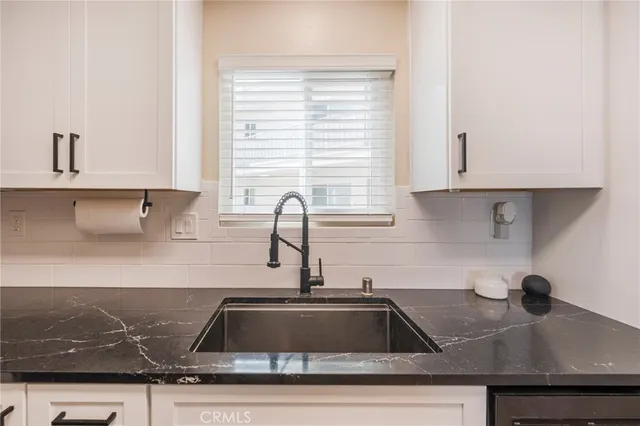a kitchen with granite countertop a sink a stove and cabinets