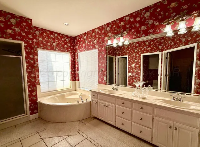 a spacious bathroom with a tub sink and mirror