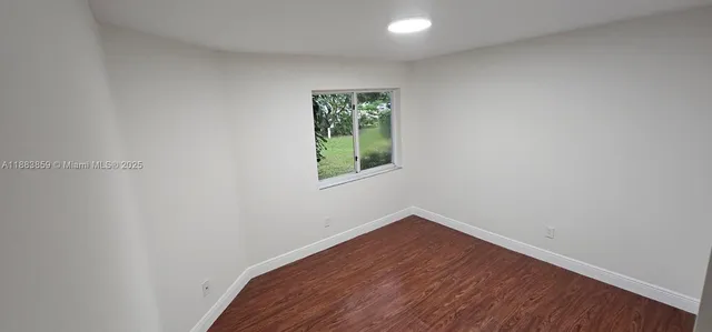 an empty room with wooden floor and front door