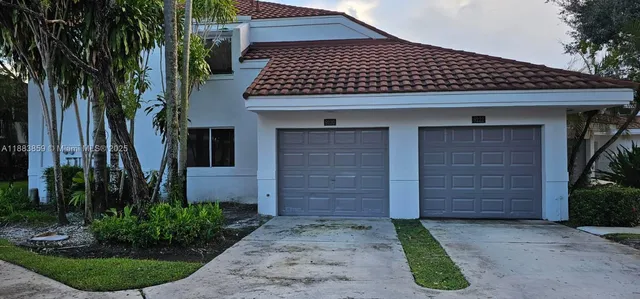a front view of a house with a yard and palm trees