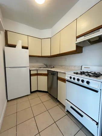 a kitchen with a white cabinets a refrigerator and a stove top oven