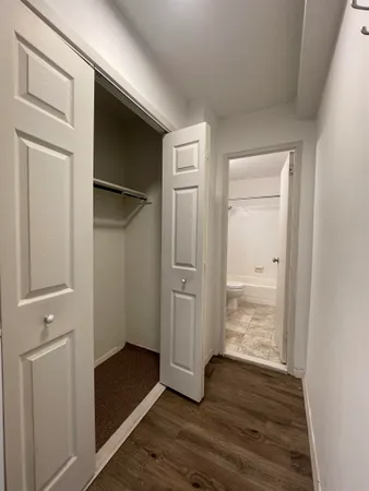 a view of an empty room with wooden floor and closet