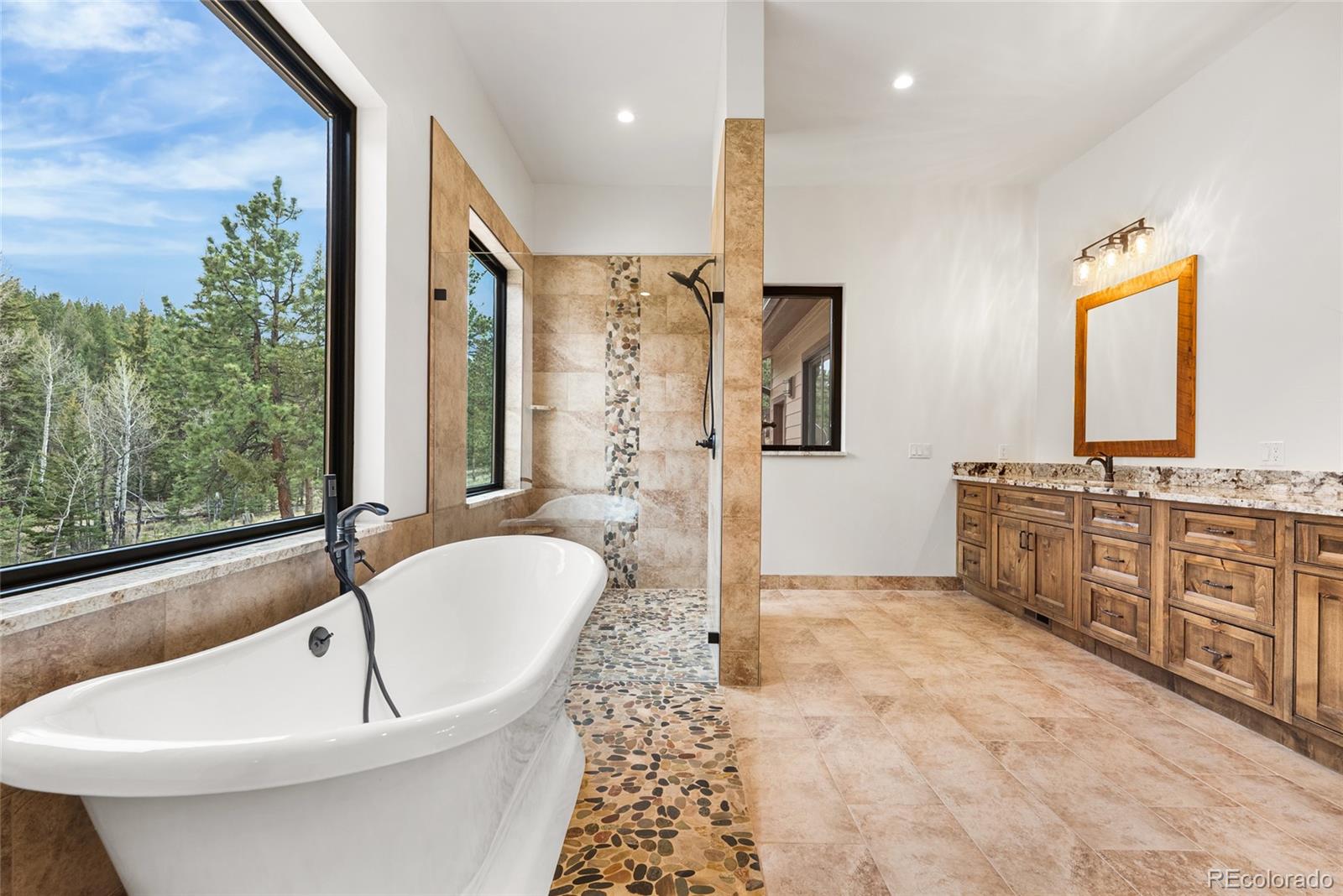 280 Double Tree Road Bailey, CO 80421 - Photo 30 of 43 a bathroom with a double vanity sink a mirror a bathtub and next to a window