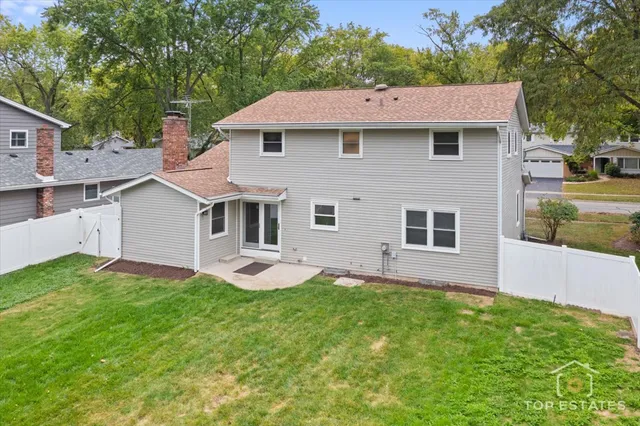 a aerial view of a house with yard and trees in the background