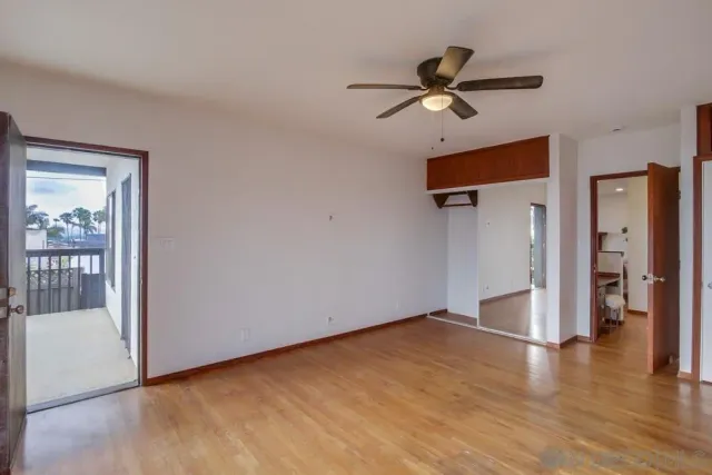 a view of an empty room with window and wooden floor