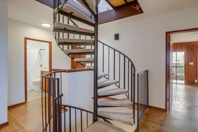 a view of staircase with lots of frames on wall and a window