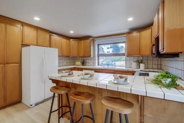 a kitchen with stainless steel appliances granite countertop a refrigerator a sink a stove a dining table and chairs