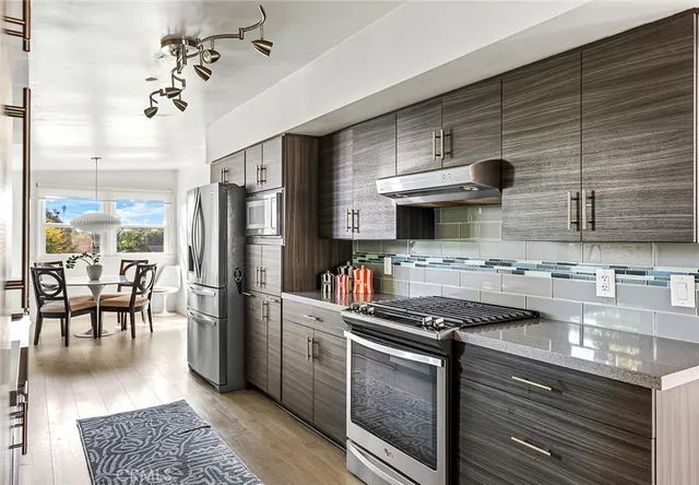 a kitchen with stainless steel appliances a stove a sink a refrigerator cabinets and a dining table