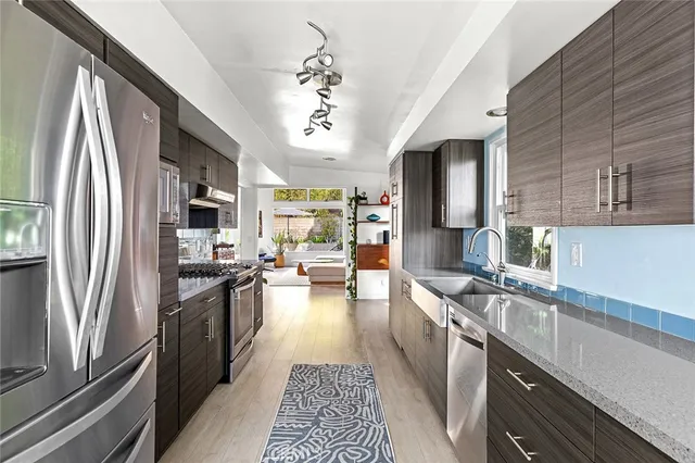 a large kitchen with stainless steel appliances granite countertop a refrigerator a stove top oven a sink dishwasher and wooden cabinets