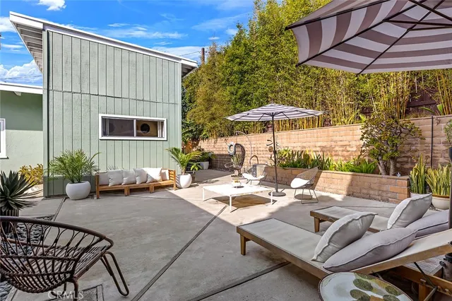 a view of a patio with couches table and chairs under an umbrella