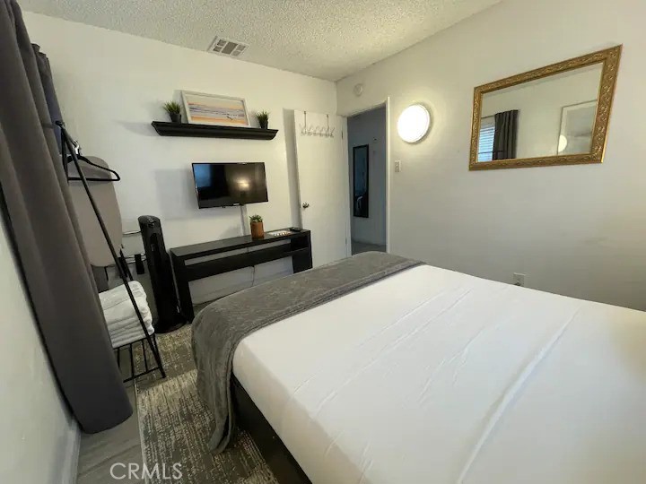 15133 Bellflower Boulevard Bellflower, CA 90706 - Photo 11 of 16 a bedroom with a bed and a flat tv screen on the dresser