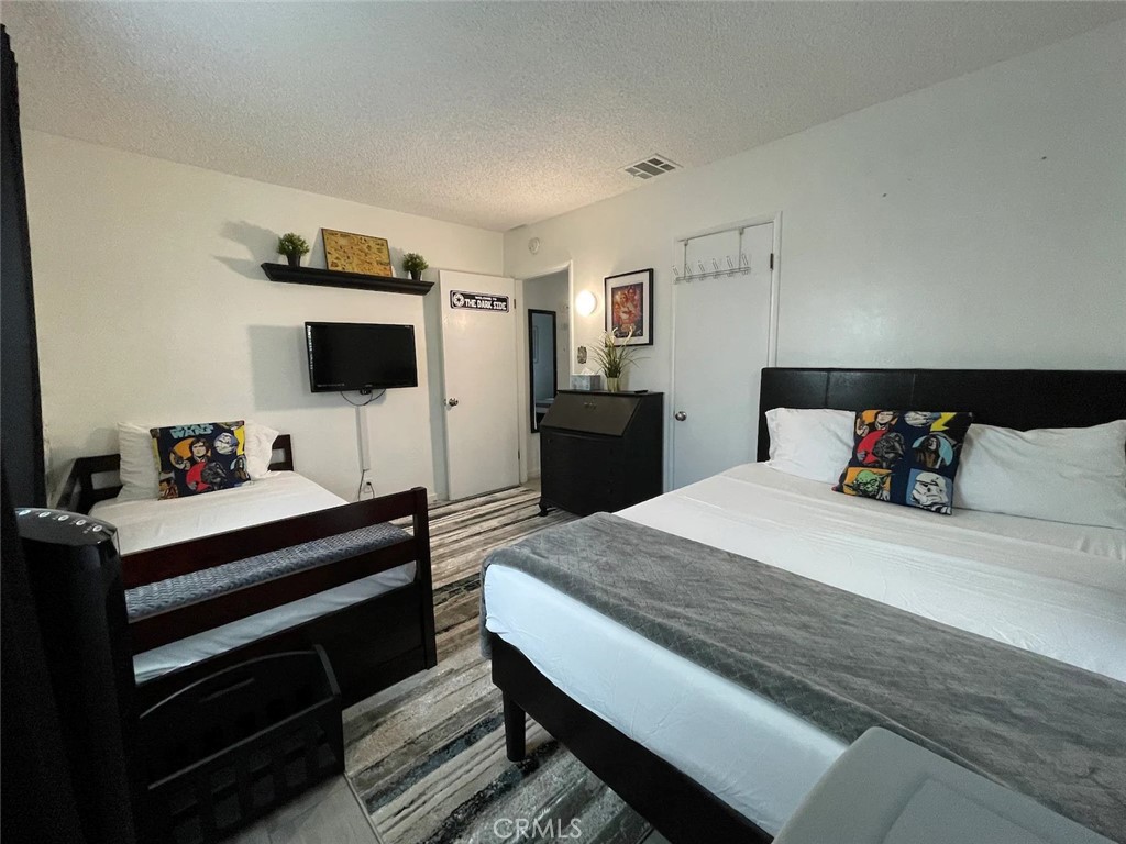 15133 Bellflower Boulevard Bellflower, CA 90706 - Photo 13 of 16 a bedroom with a bed and a flat screen tv