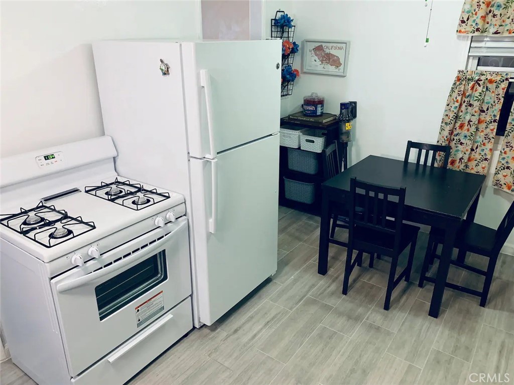 15133 Bellflower Boulevard Bellflower, CA 90706 - Photo 8 of 16 a kitchen with a stove a refrigerator and a dining table