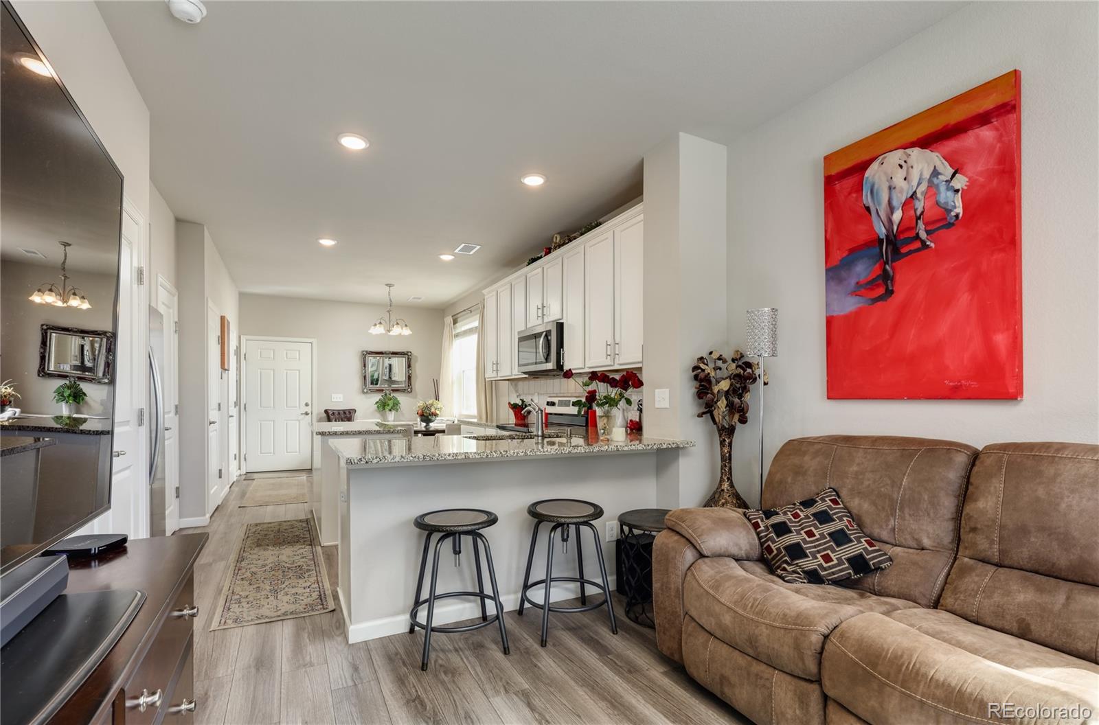 a living room with stainless steel appliances furniture and a wooden floor
