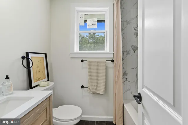 a bathroom with a granite countertop toilet a sink and a mirror