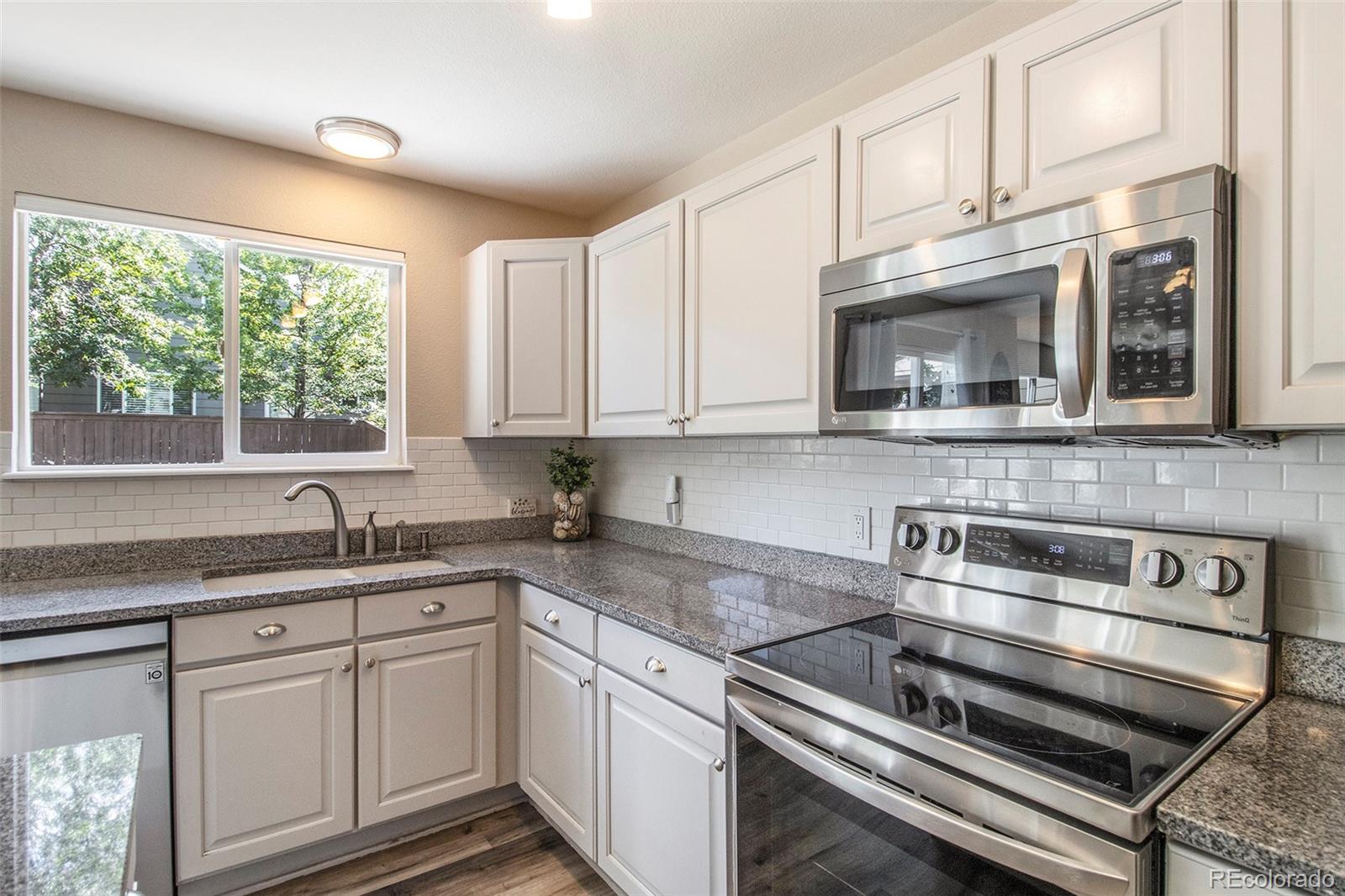 822 Timbervale Trail Highlands Ranch, CO 80129 - Photo 2 of 34 a kitchen with granite countertop white cabinets stainless steel appliances and a window