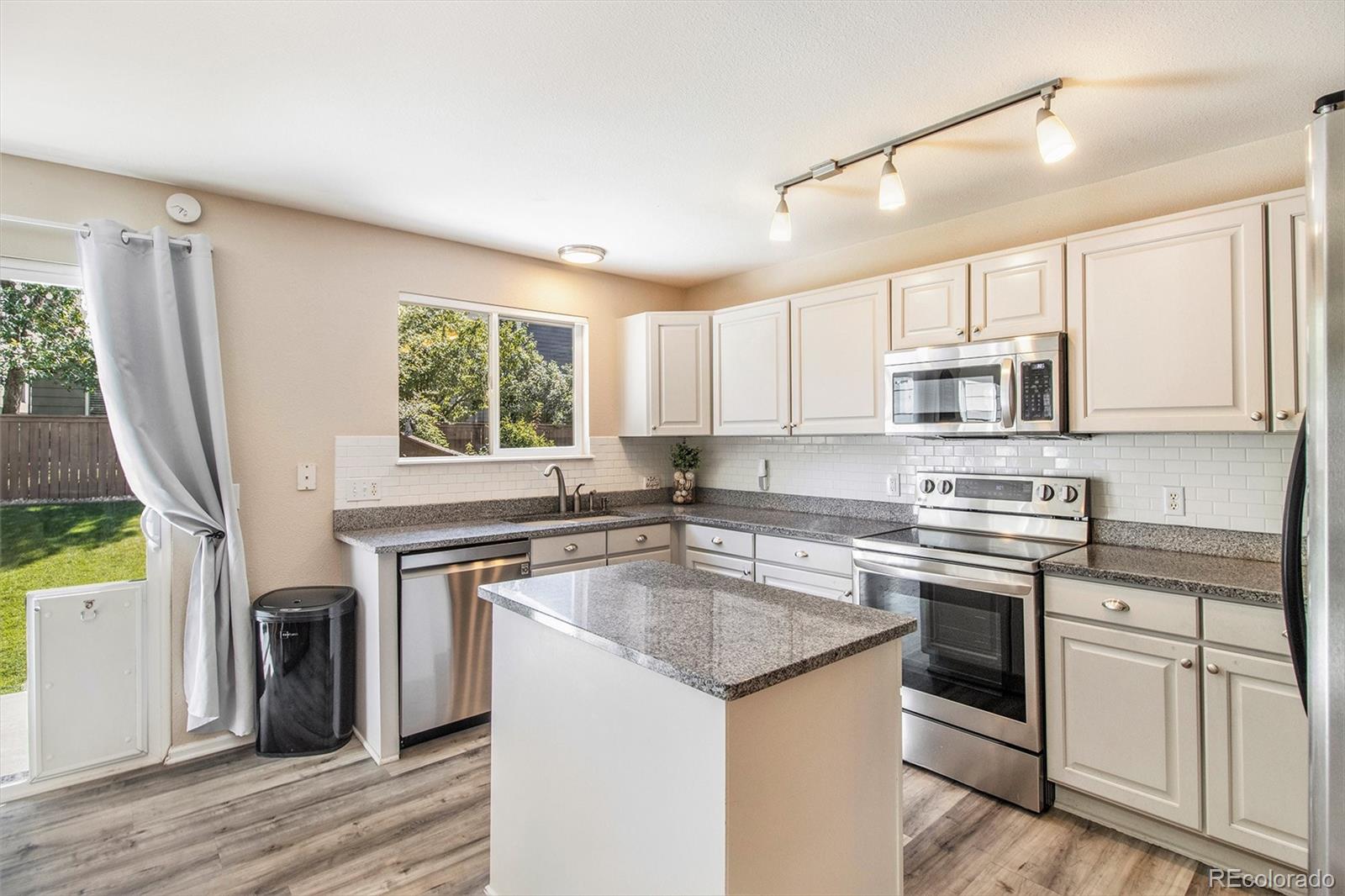 822 Timbervale Trail Highlands Ranch, CO 80129 - Photo 3 of 34 a kitchen with stainless steel appliances granite countertop a stove a sink dishwasher a microwave oven and a refrigerator with wooden floor