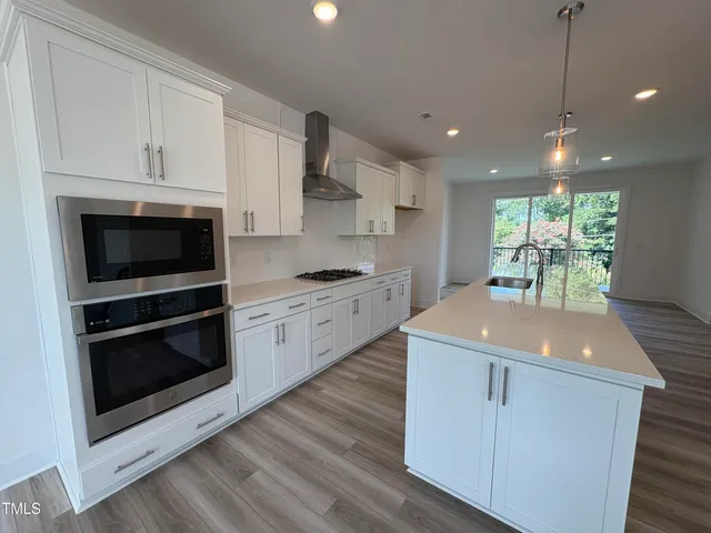 a kitchen with stainless steel appliances granite countertop a stove a microwave and a white cabinets