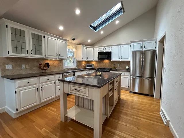 a kitchen with stainless steel appliances granite countertop a stove refrigerator sink and microwave