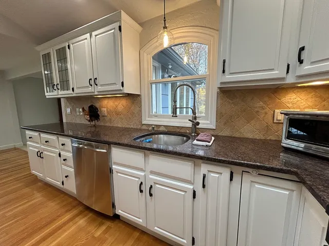 a kitchen with granite countertop white cabinets and stainless steel appliances