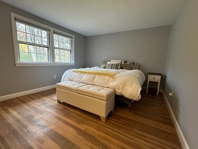 a spacious bedroom with a bed and wooden floor