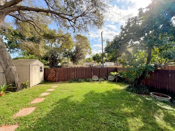 a view of a backyard with large trees and wooden fence