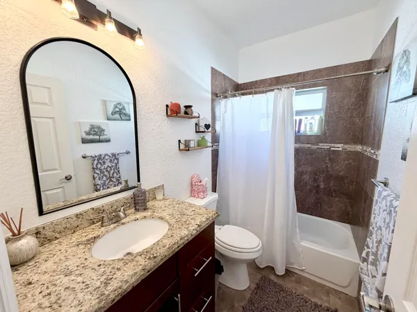 a bathroom with a granite countertop sink a toilet and shower