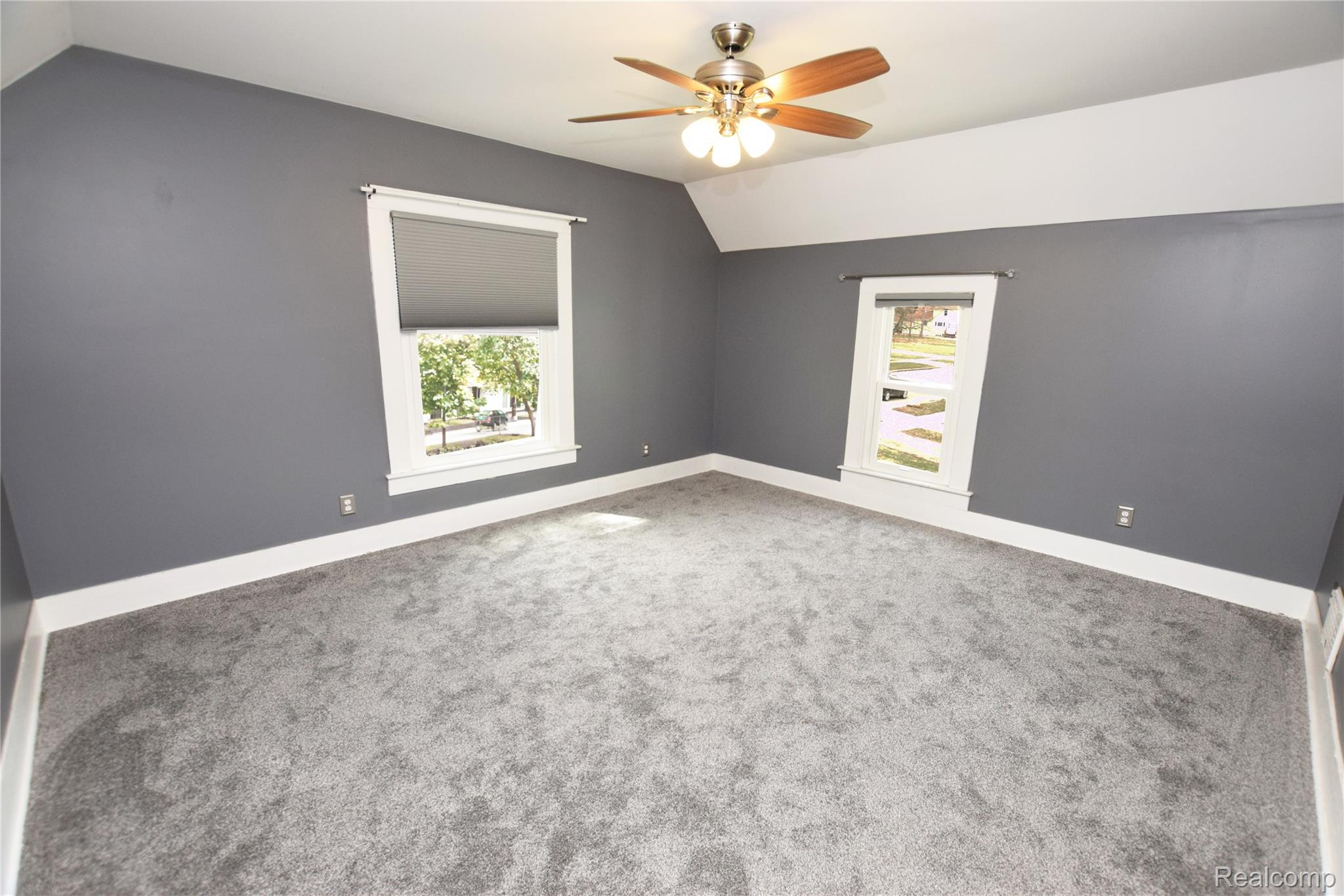 404 North Adelaide Street Fenton, MI 48430 - Photo 14 of 23 Carpeted room featuring gray walls, white trim, two windows with window treatments, and an overhead ceiling fan with light fixture