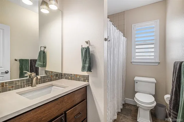 a bathroom with a granite countertop sink toilet and shower