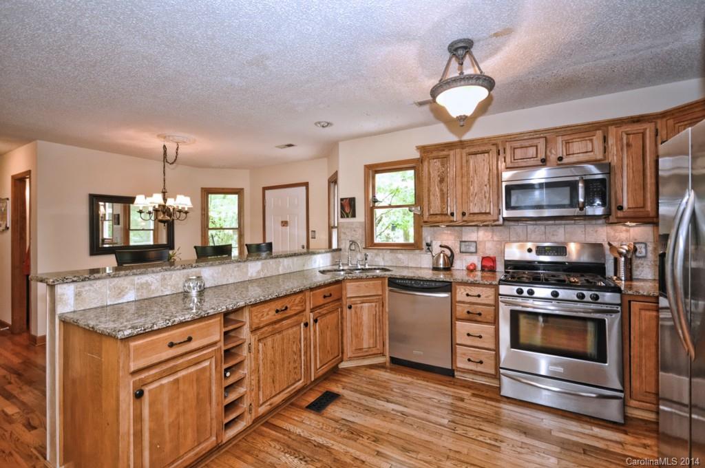 31017 Executive Point Tega Cay, SC 29708 - Photo 2 of 22 a kitchen with stainless steel appliances granite countertop a stove top oven a sink dishwasher a dining table and chairs with wooden floor