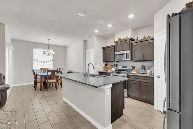 a open kitchen with stainless steel appliances granite countertop a sink dishwasher a stove and a refrigerator with wooden floor