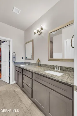a en suite bathroom with a granite countertop sink and a mirror