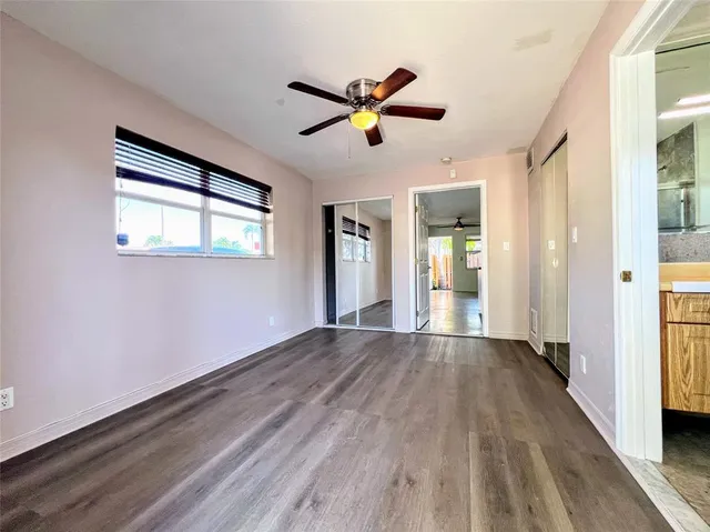 a view of empty room with wooden floor and fan