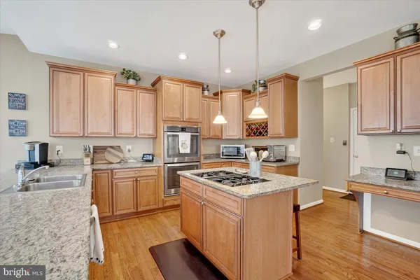 a kitchen with stainless steel appliances kitchen island granite countertop a stove a sink dishwasher and a microwave with wooden floor