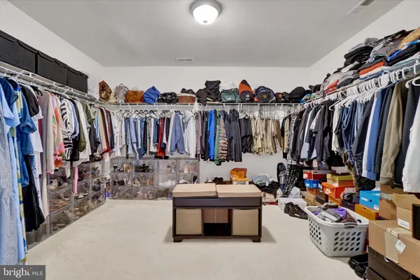 a view of walk in closet with clothes and shoes