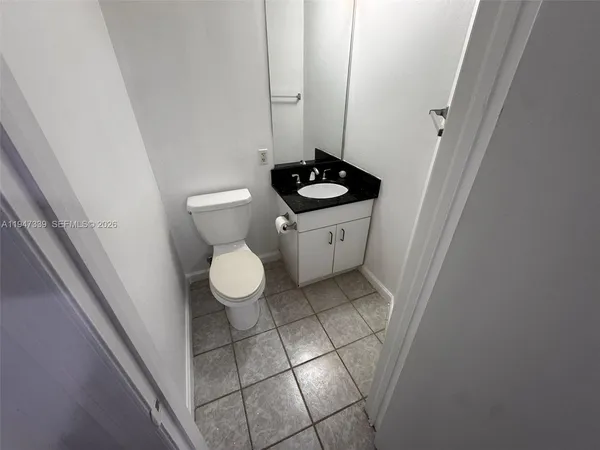 a bathroom with a granite countertop sink and a toilet