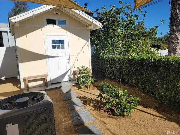 a view of a backyard with potted plants and large tree