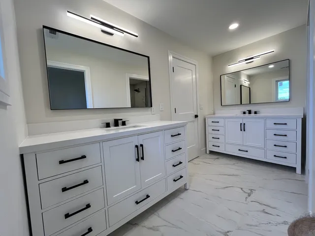a bathroom with a double vanity sink mirror and bathtub