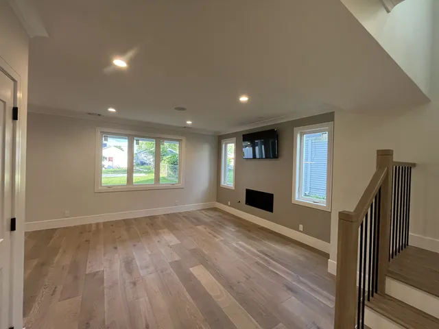 a view of an empty room with wooden floor fireplace and a window